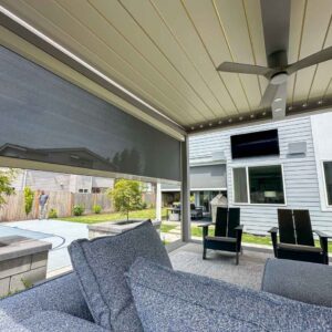 Inside pergola view of motorized solar shade halfway down on custom pergola with closed louvers